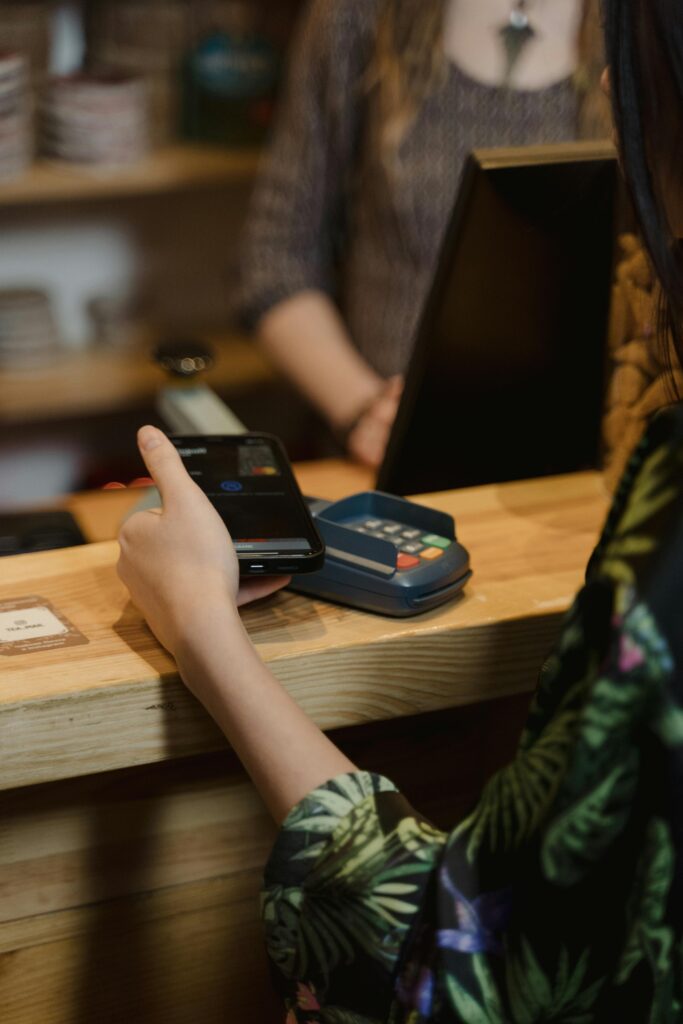 A person using mobile to make a contactless payment at a café counter.