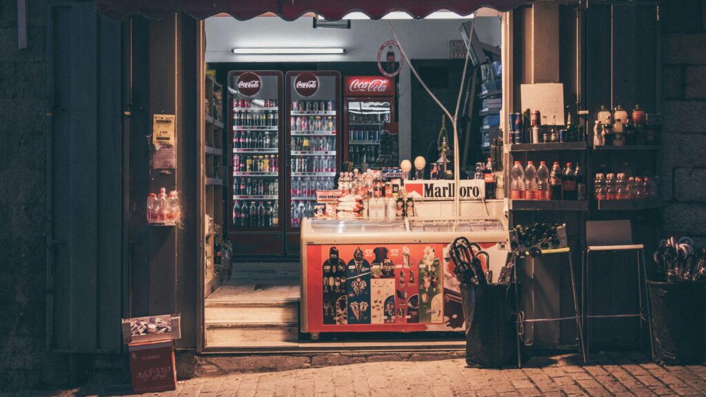 Convenience store with a variety of drinks and products under warm evening light.